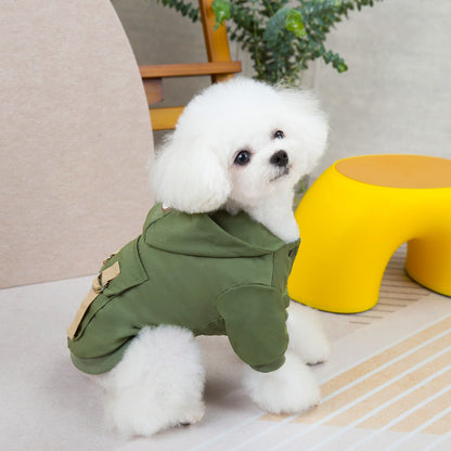 Small white dog wearing a green hooded pet coat, viewed from the side