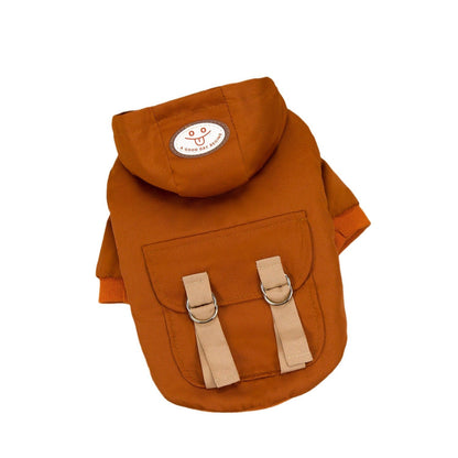 Rust-brown hooded pet coat with a smiley patch and backpack-style flap and straps