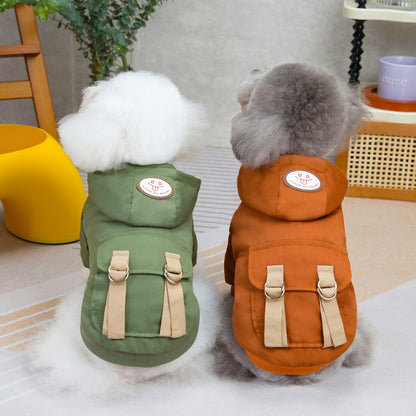 Two small dogs wearing green and rust-brown hooded pet coats, showing backpack-style back details