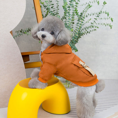 Small gray dog wearing a rust-brown hooded pet coat, viewed from the side