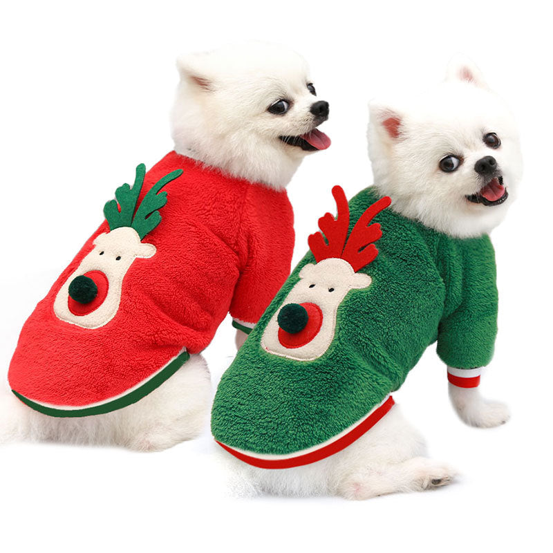 Two small white dogs wearing red and green reindeer fleece sweaters