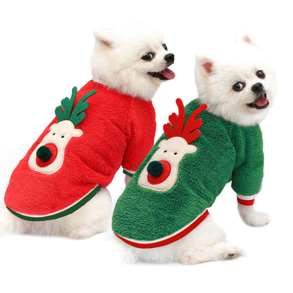Two small white dogs wearing red and green reindeer fleece sweaters