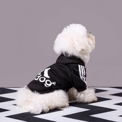 Dog wearing a black Adidog hoodie with white back graphics and shoulder stripes
