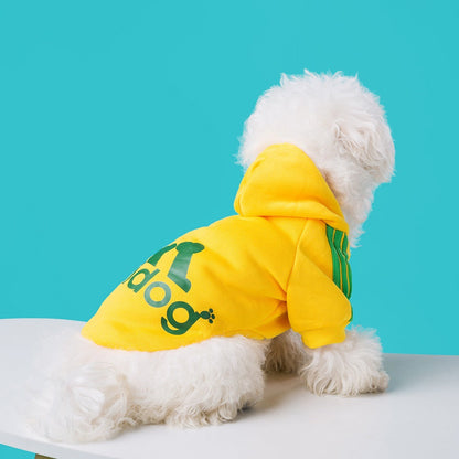 Dog wearing a yellow Adidog hoodie with green back graphics and shoulder stripes