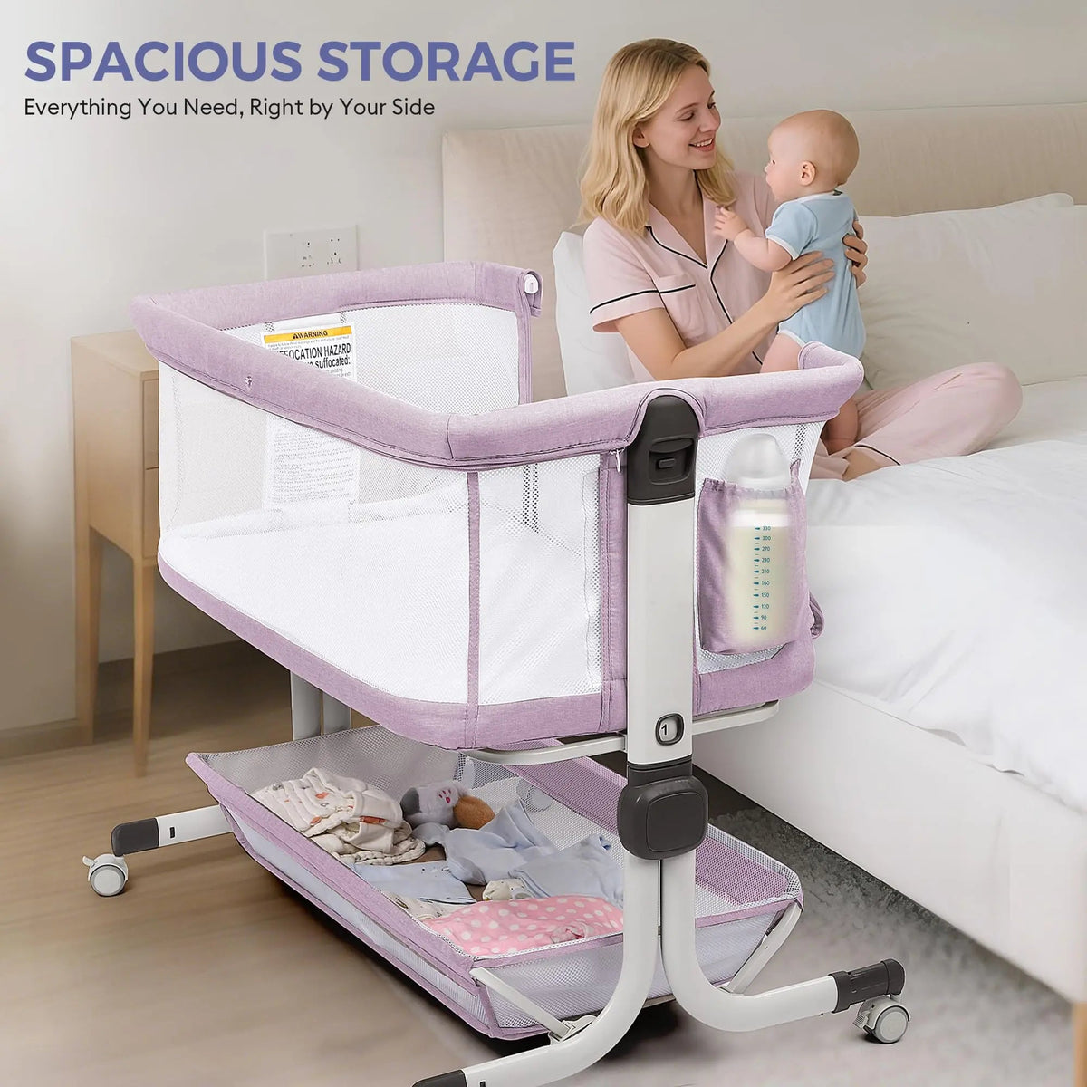 Mother holding a baby beside a lavender bassinet with a side pocket and lower storage shelf.