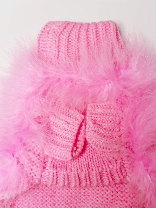 Underside of a pink fluffy pet sweater, showing two knitted sleeve openings and a ribbed hem