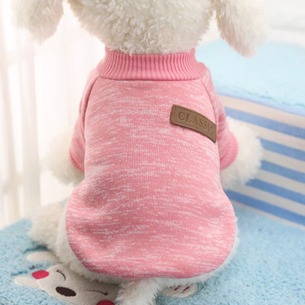Close-up of a pink pet sweater showing its ribbed neckline and decorative CLASSIC back patch