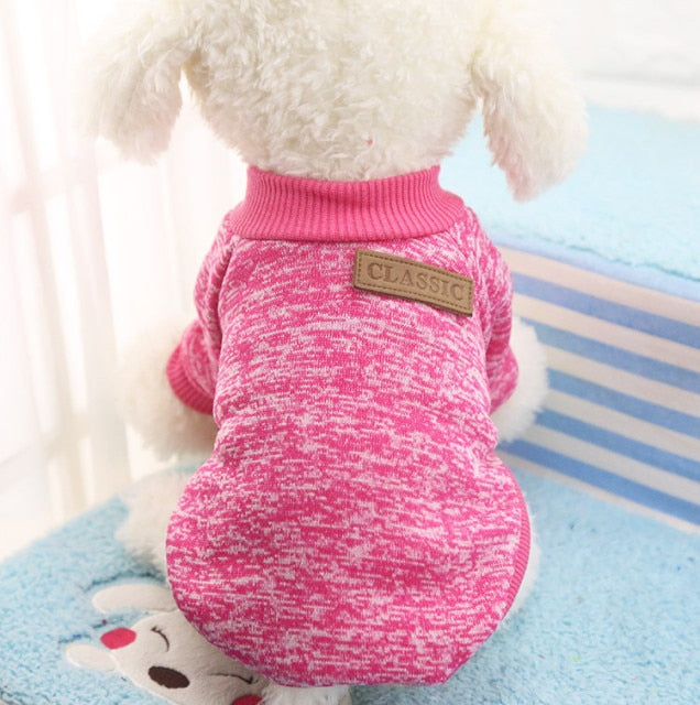 Rose marled pullover pet sweater with ribbed trim and a decorative back patch on a white plush dog