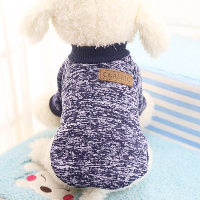 Navy marled pullover pet sweater with ribbed trim and a decorative back patch on a white plush dog