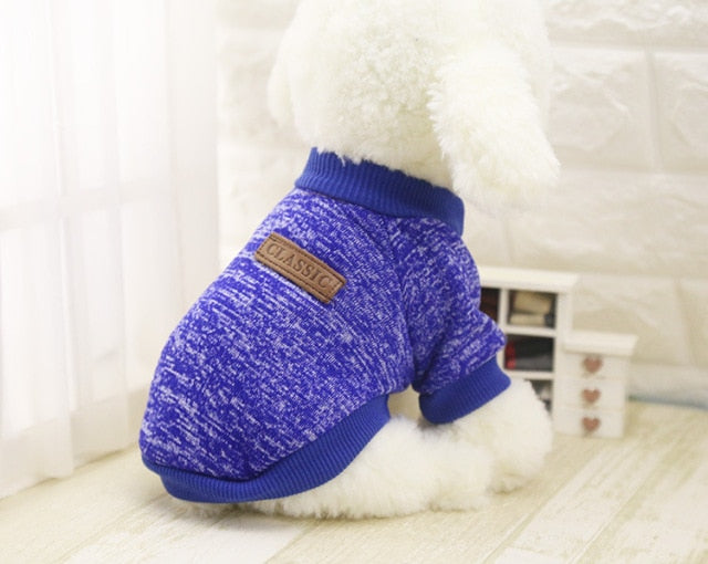 Deep blue marled pet sweater with short sleeves and ribbed trim, shown from the side on a white plush dog